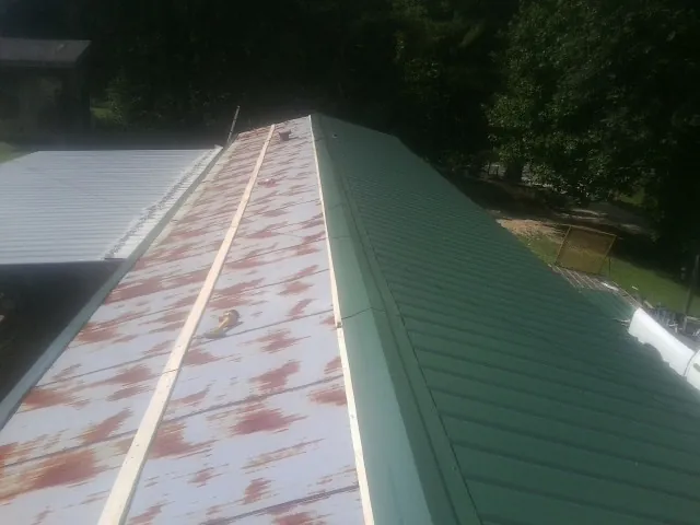 Old rusted panels beside newly installed green metal roofing — Wind Damage Roof Repair by Roofing Brothers in Newfield
