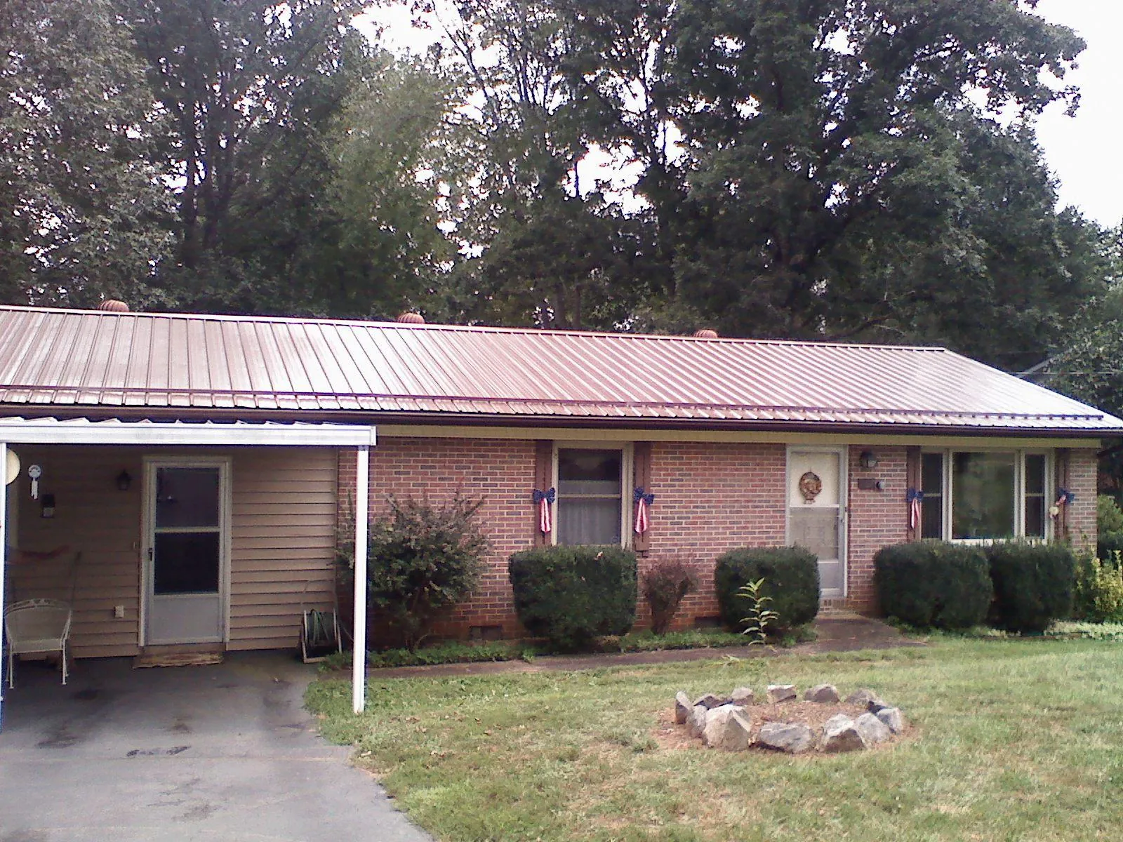 Bronze metal roof and carport on a brick ranch home — Roof Repair work by our crew in Newfield